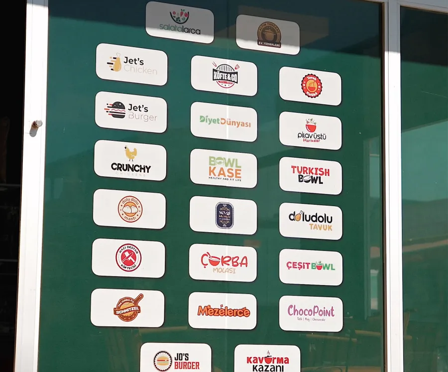 Mizanplus markalarının logolarıyla kaplı mağaza panosu